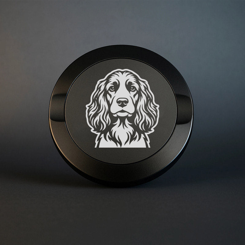 Mattsvart snusdosa i metall med detaljrik lasergravyr av en cocker spaniel på locket, fotograferad mot en mörk, stilren bakgrund som framhäver gravyrens skarpa detaljer.