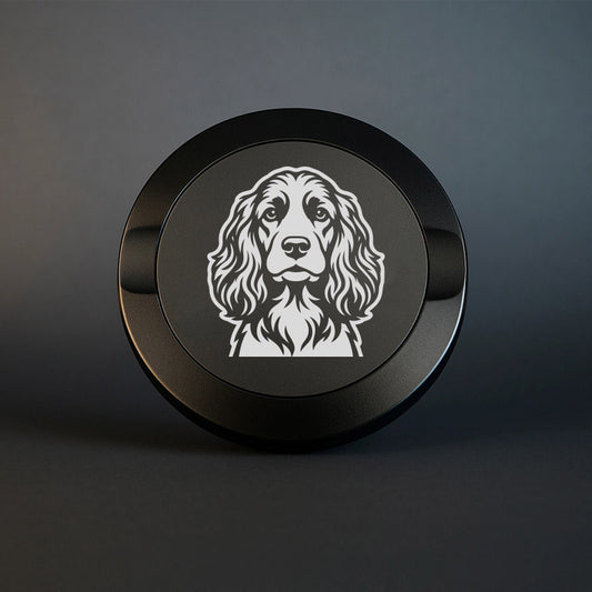 Mattsvart snusdosa i metall med detaljrik lasergravyr av en cocker spaniel på locket, fotograferad mot en mörk, stilren bakgrund som framhäver gravyrens skarpa detaljer.