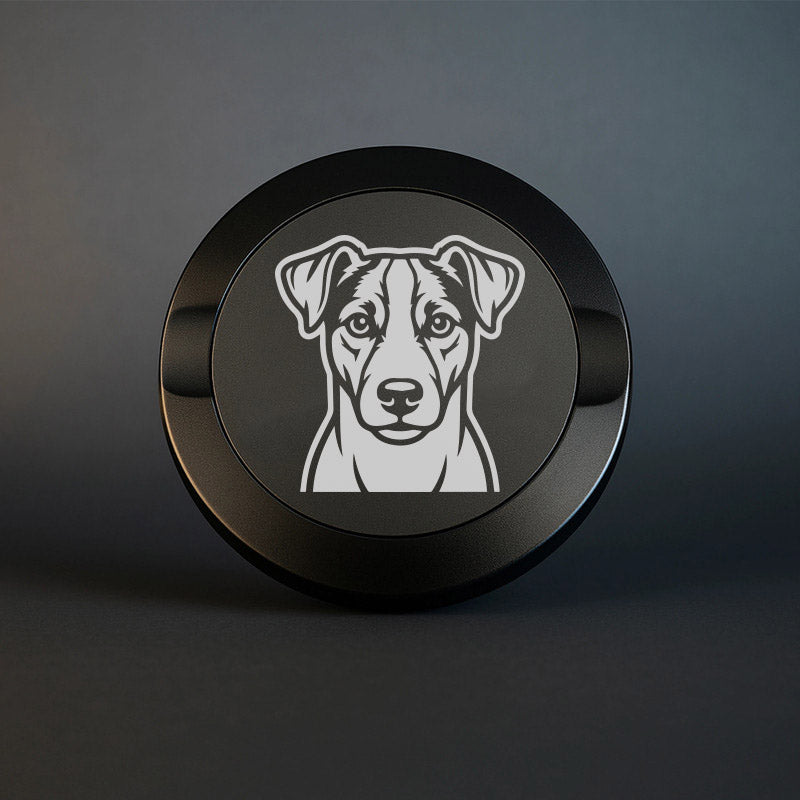 Mattsvart snusdosa i metall med detaljrik lasergravyr av en jack russell terrier på locket, fotograferad mot en mörk, stilren bakgrund som framhäver gravyrens skarpa detaljer.