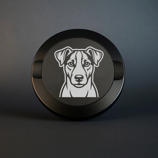 Mattsvart snusdosa i metall med detaljrik lasergravyr av en jack russell terrier på locket, fotograferad mot en mörk, stilren bakgrund som framhäver gravyrens skarpa detaljer.
