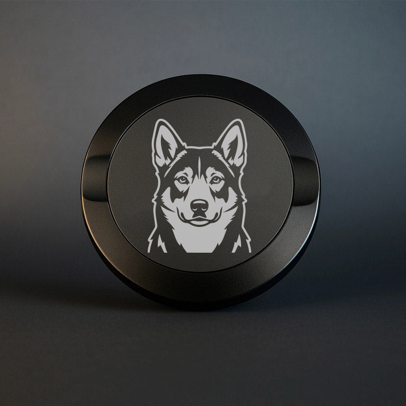 Mattsvart snusdosa i metall med detaljrik lasergravyr av en jämthund på locket, fotograferad mot en mörk, stilren bakgrund som framhäver gravyrens skarpa detaljer.