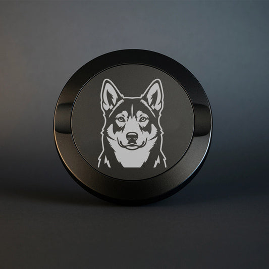 Mattsvart snusdosa i metall med detaljrik lasergravyr av en jämthund på locket, fotograferad mot en mörk, stilren bakgrund som framhäver gravyrens skarpa detaljer.