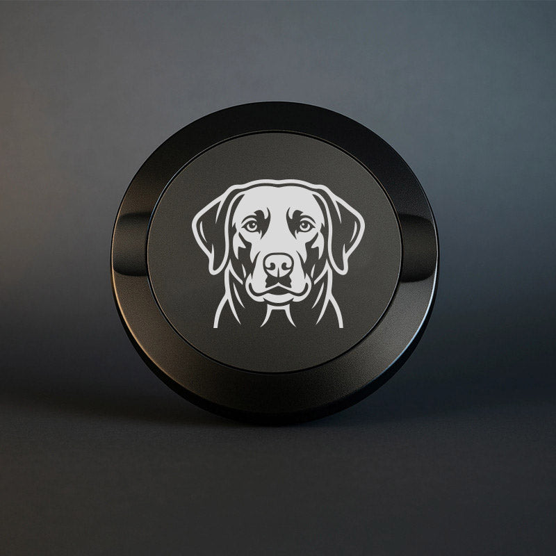 Mattsvart snusdosa i metall med detaljrik lasergraverad labrador på locket, fotograferad mot en mörk stilren bakgrund som framhäver gravyrens skarpa detaljer.