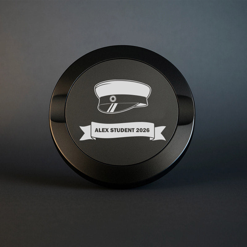Svart snusdosa i metall med ingraverad studentmössa och en banderoll med texten Alex student 2026