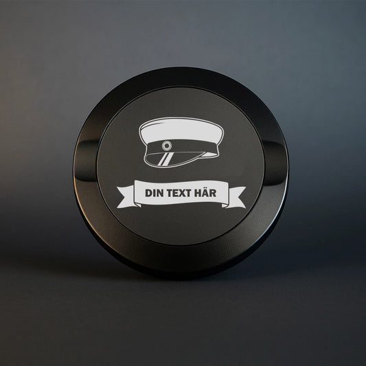 Svart snusdosa i metall med ingraverad studentmössa och en banderoll med plats för valfri text. Perfekt som studentpresent.